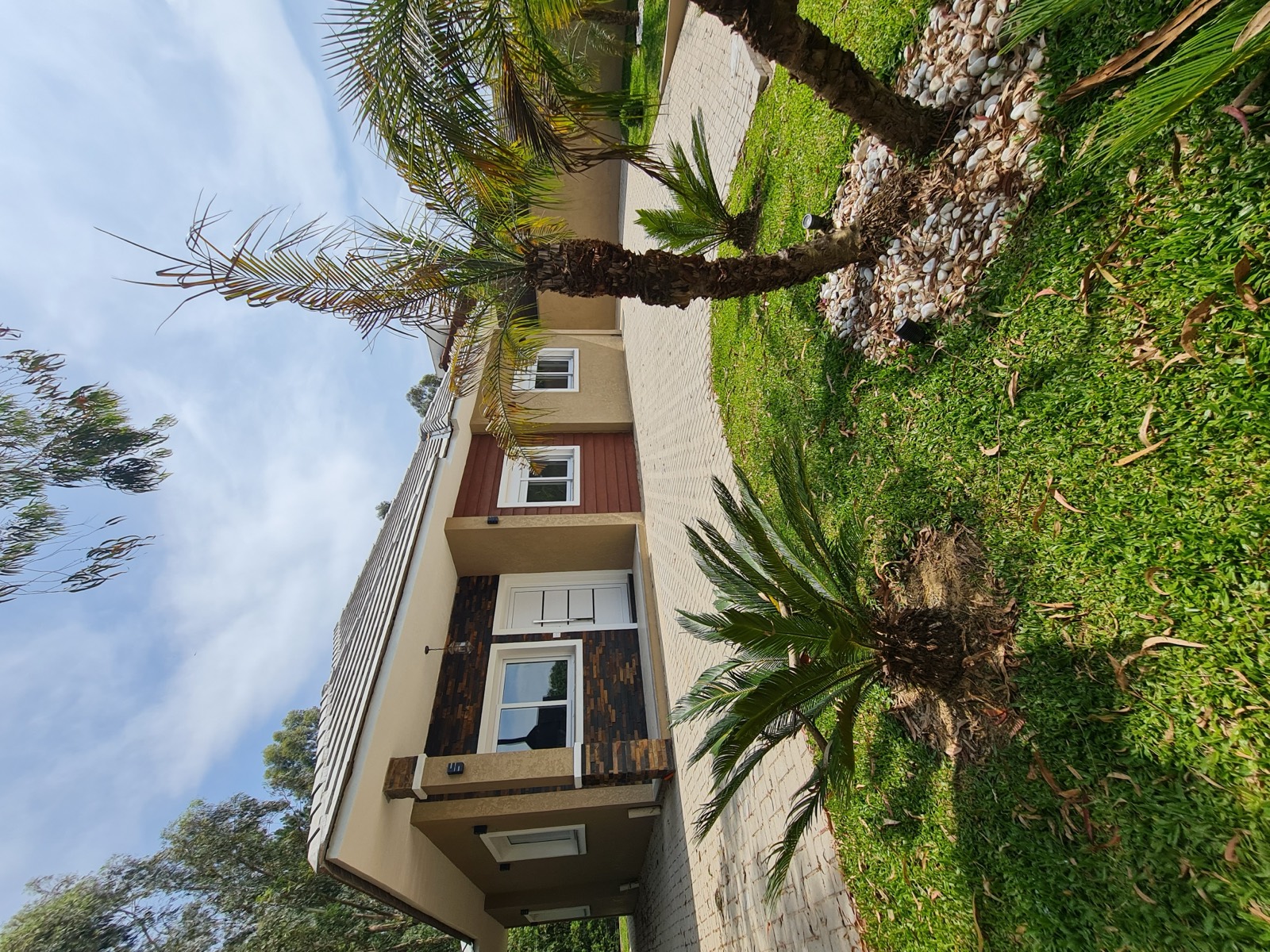 Fachada da casa térrea nova com jardim e palmeiras
